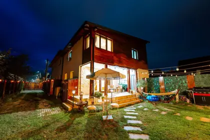 Casa seara, cu terasa și luminile din grădină